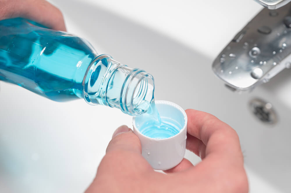 man Pouring Bottle Of Mouthwash Into Cap