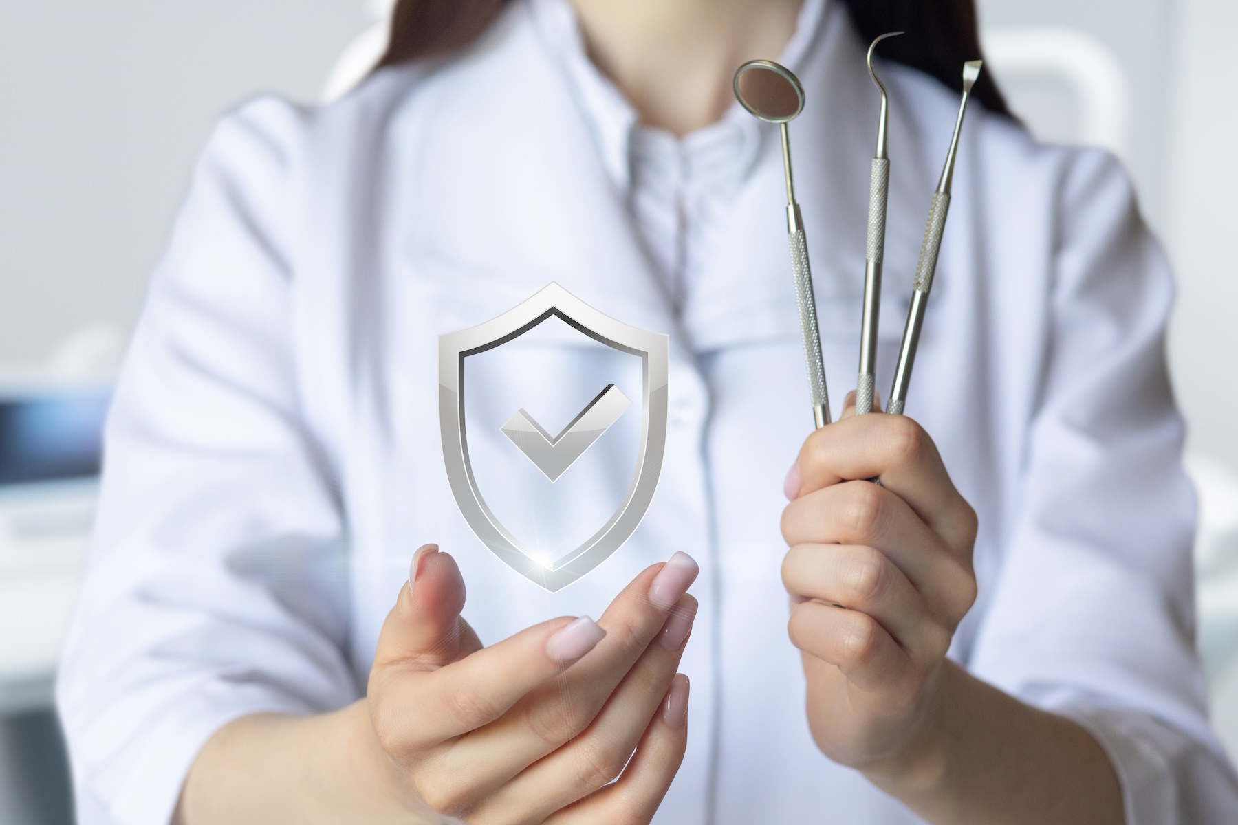 The concept of guaranteed quality of dental treatment. The dentist shows a shield with a checkmark and instruments in her hand.